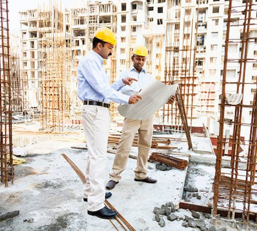 engineer and architect discussing blueprint on construction site in India